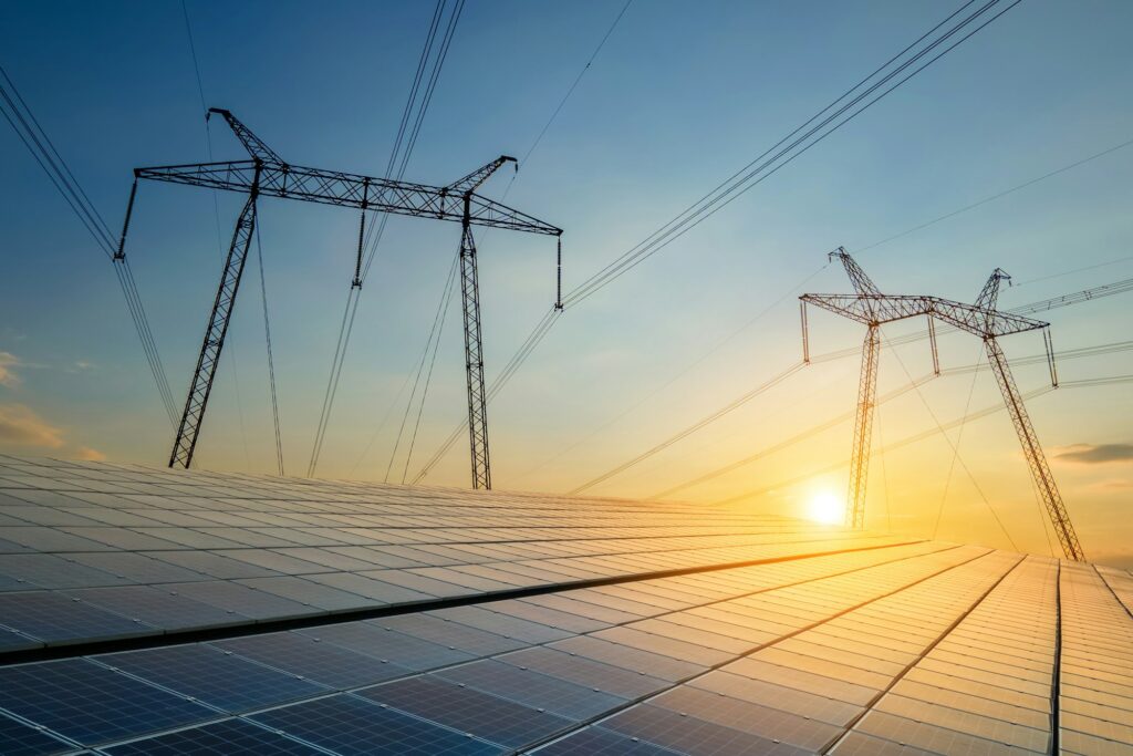 High voltage towers with electric power lines transfering energy from solar photovoltaic panels at